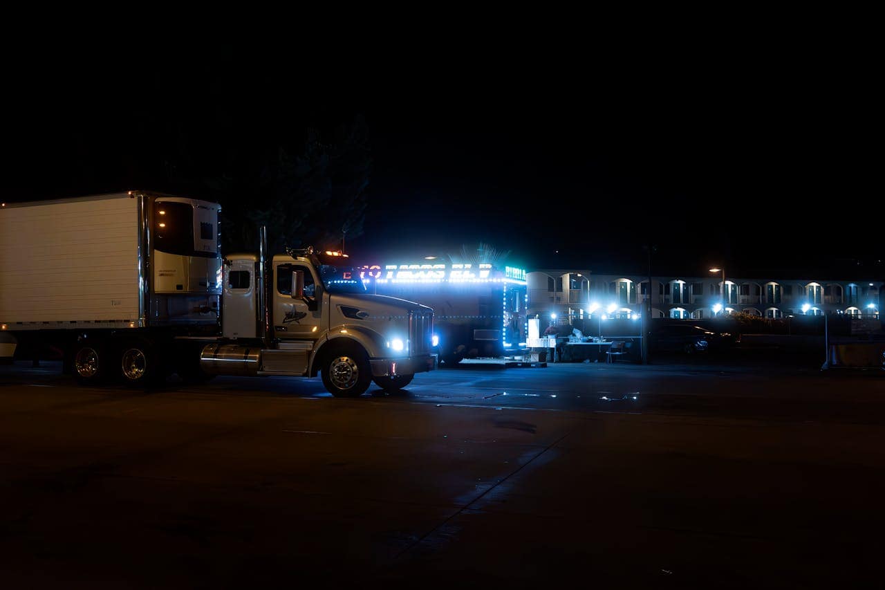 our-story Two brightly lit trucks parked in an urban area at night, showcasing their vibrant lights.